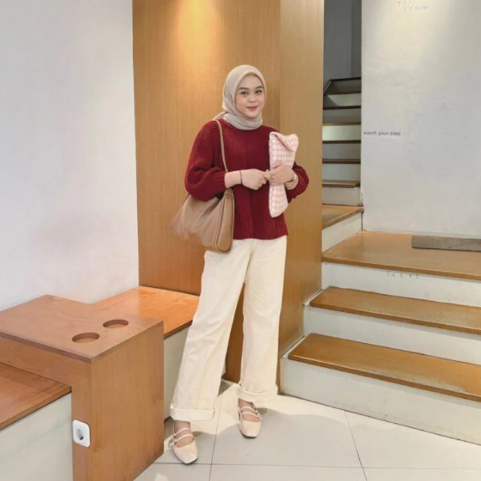 Wanita Indonesia berhijab memakai atasan sweater bahan rajut berwarna merah marun, jilbab dan celana panjang warna krem. l Instagram/adzraafifah