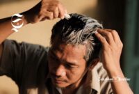 Seorang pria mewarnai rambut beruban dengan cat rambut warna hitam - sukabumiheadline.com